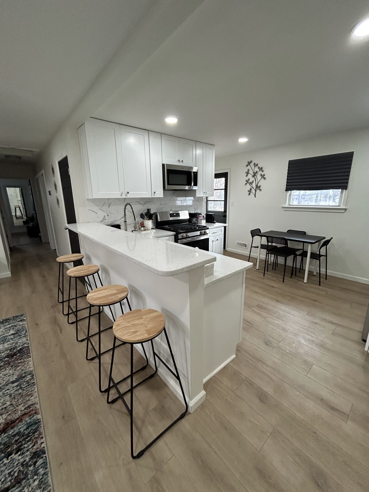 Bright white kitchen with island, stools, and wood floors, finished by Rise Builders