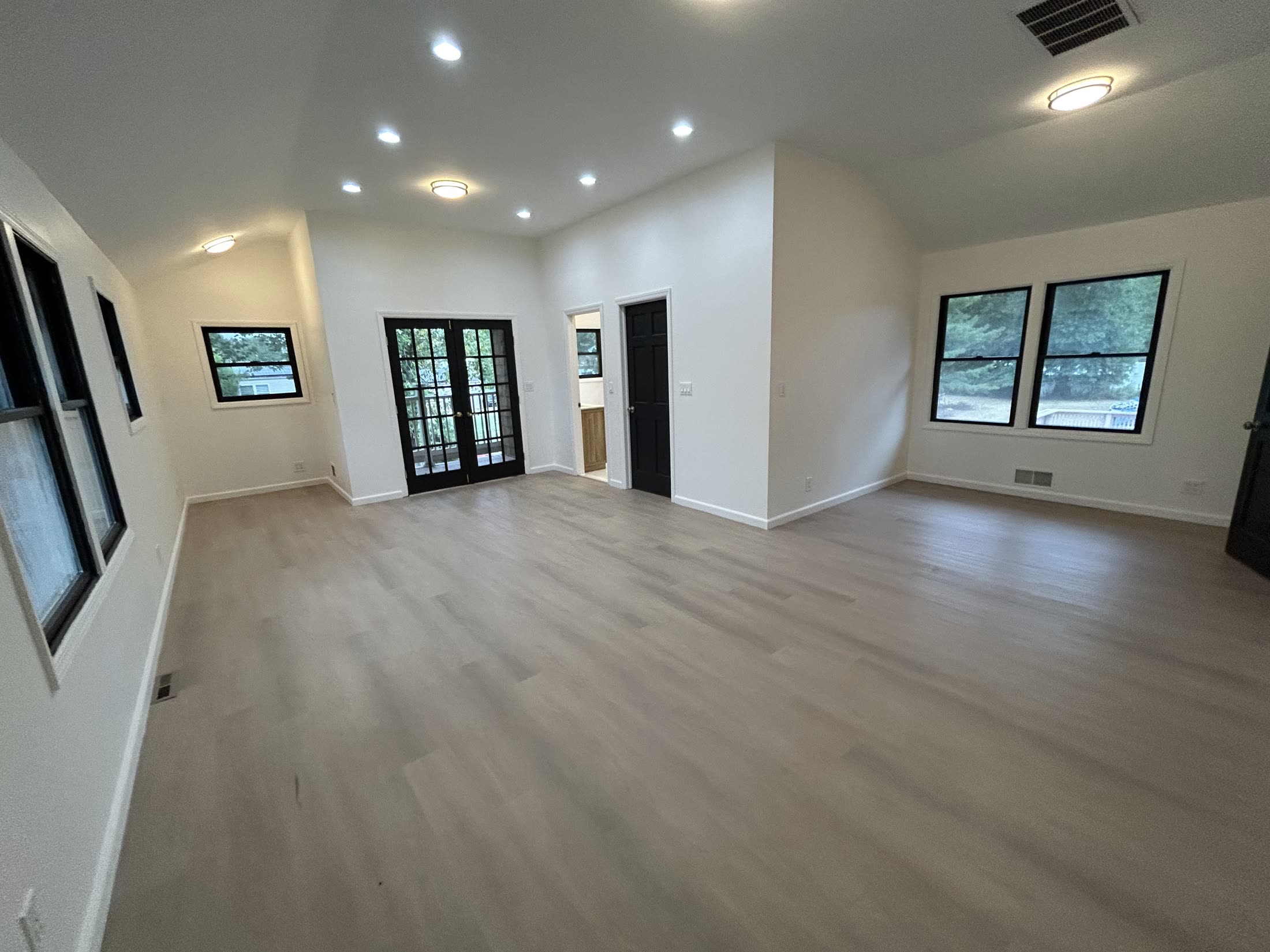 Finished bright living room with wide-plank floors and black-trim windows by Rise Builders